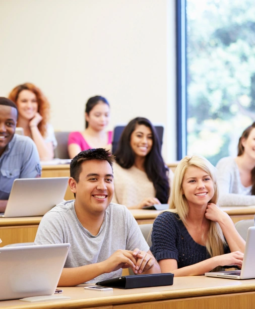 Engaged students discuss and learn via laptops in a vibrant training for abroad study entrance exams.